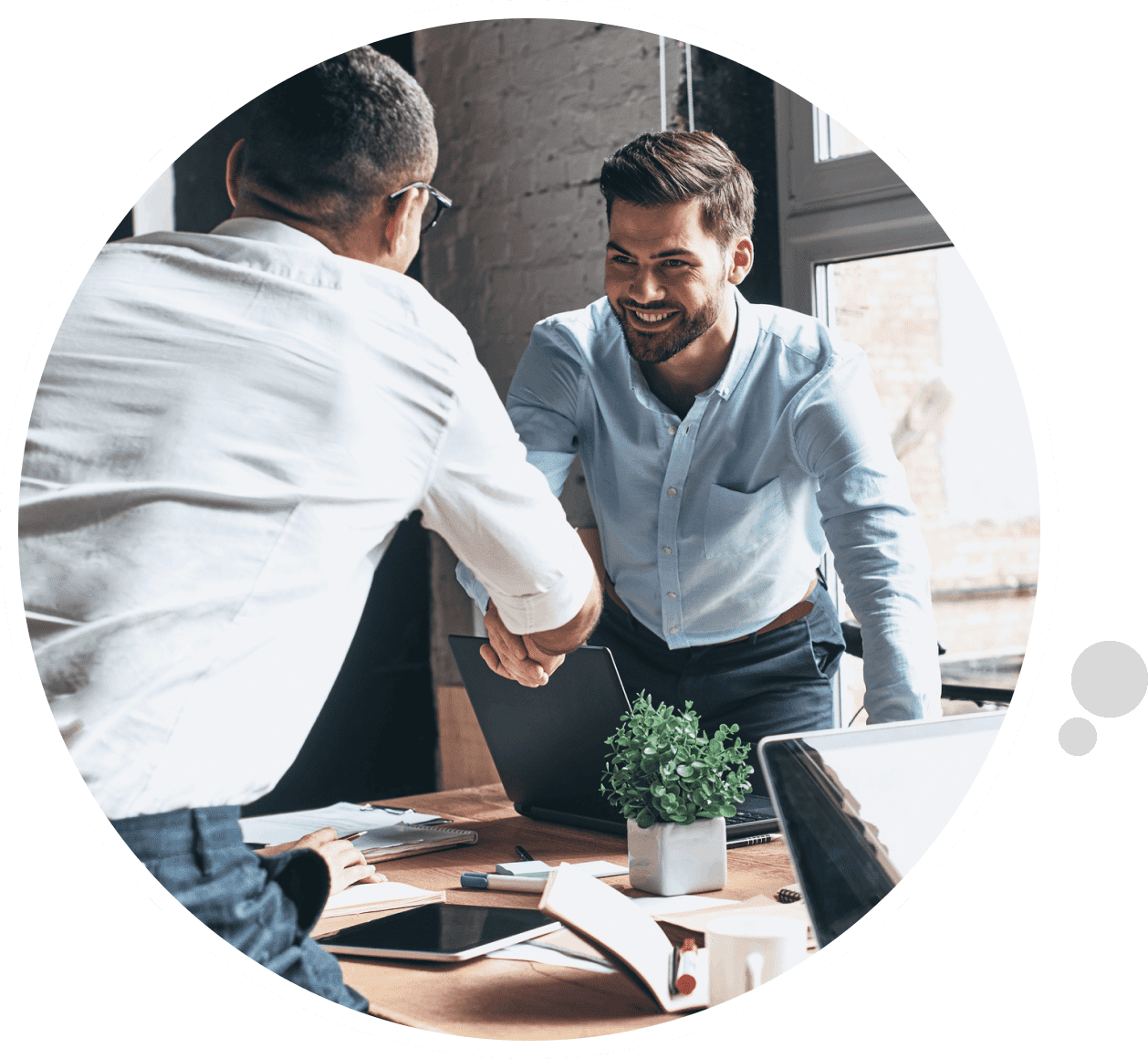 Two men shaking hands in front of a table.