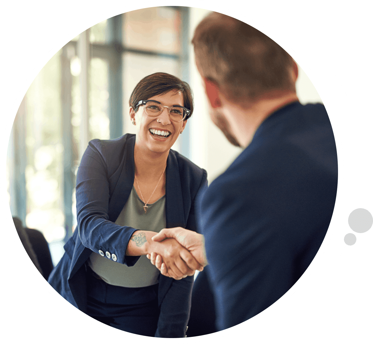 A woman shaking hands with another man in front of a window.